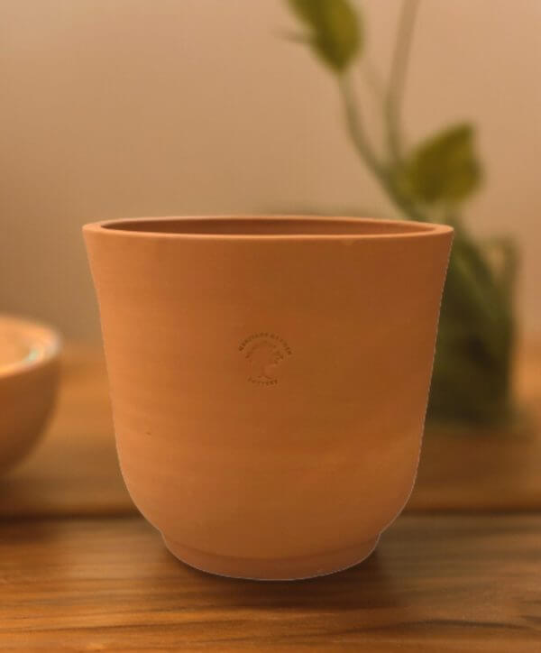 cup shaped small clay pot on wooden table