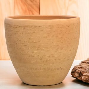 clay planter on wooden floor with a stone on side.