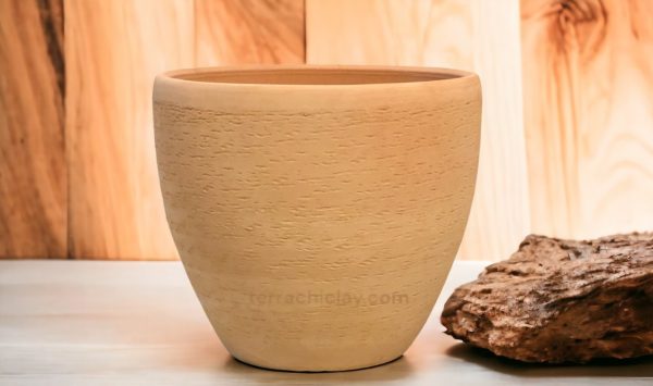 clay planter on wooden floor with a stone on side.