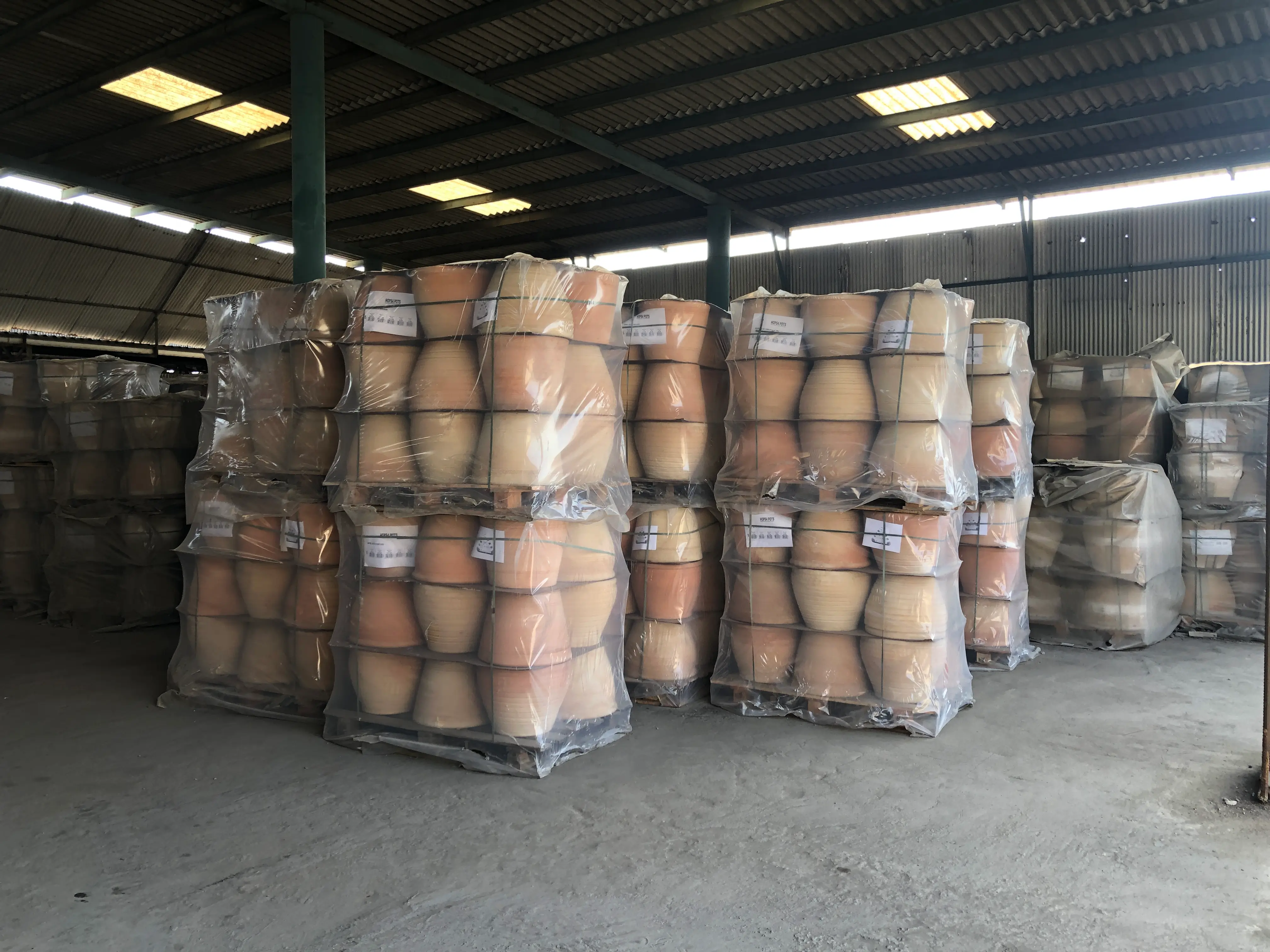 Collection of handmade terracotta pots in multiple standard sizes arranged from small herb pots to extra-large landscape containers